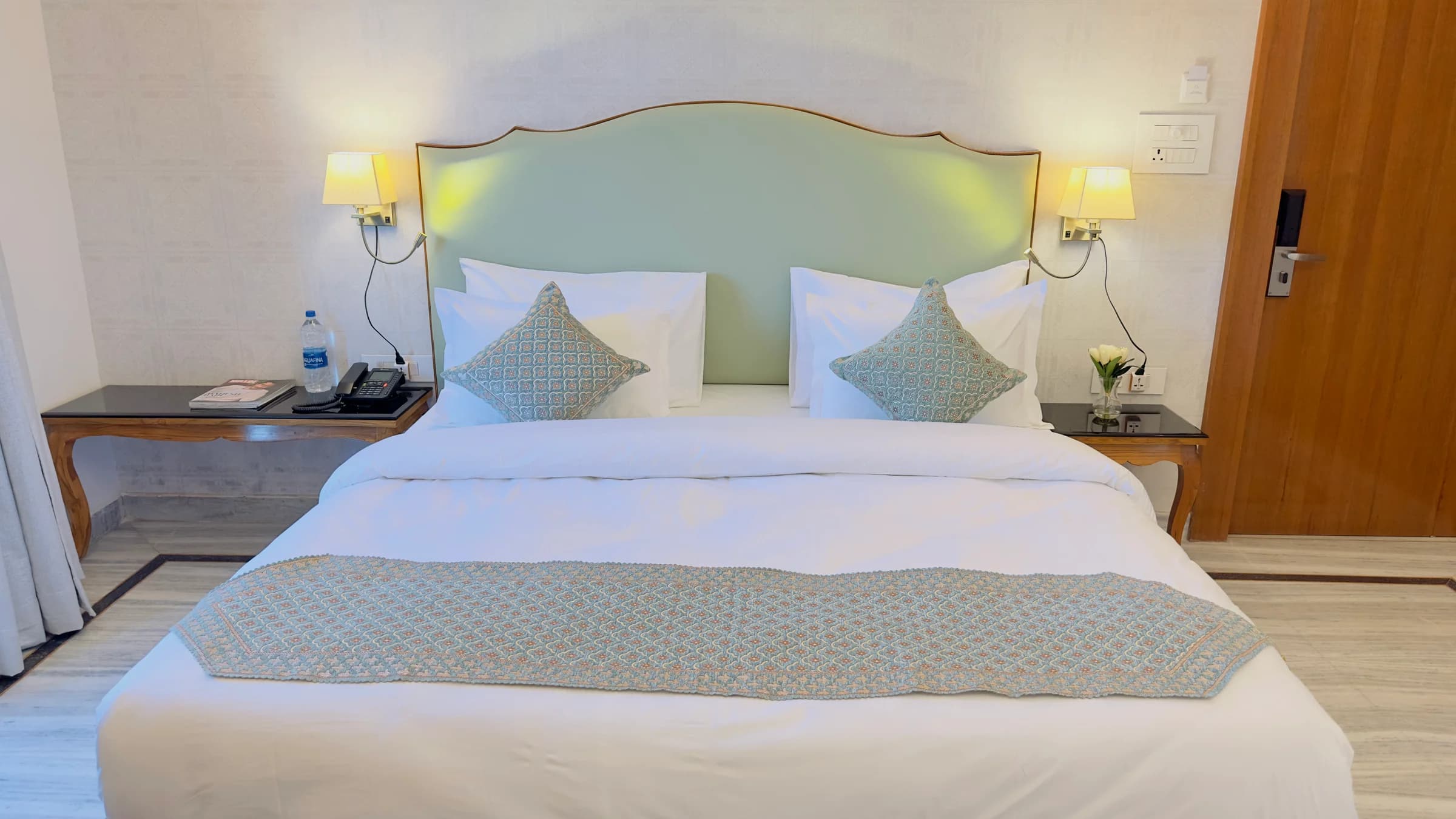 Cozy Haven at The Mohua, with a curved green headboard, white linen, patterned blue runner and bedside tables
