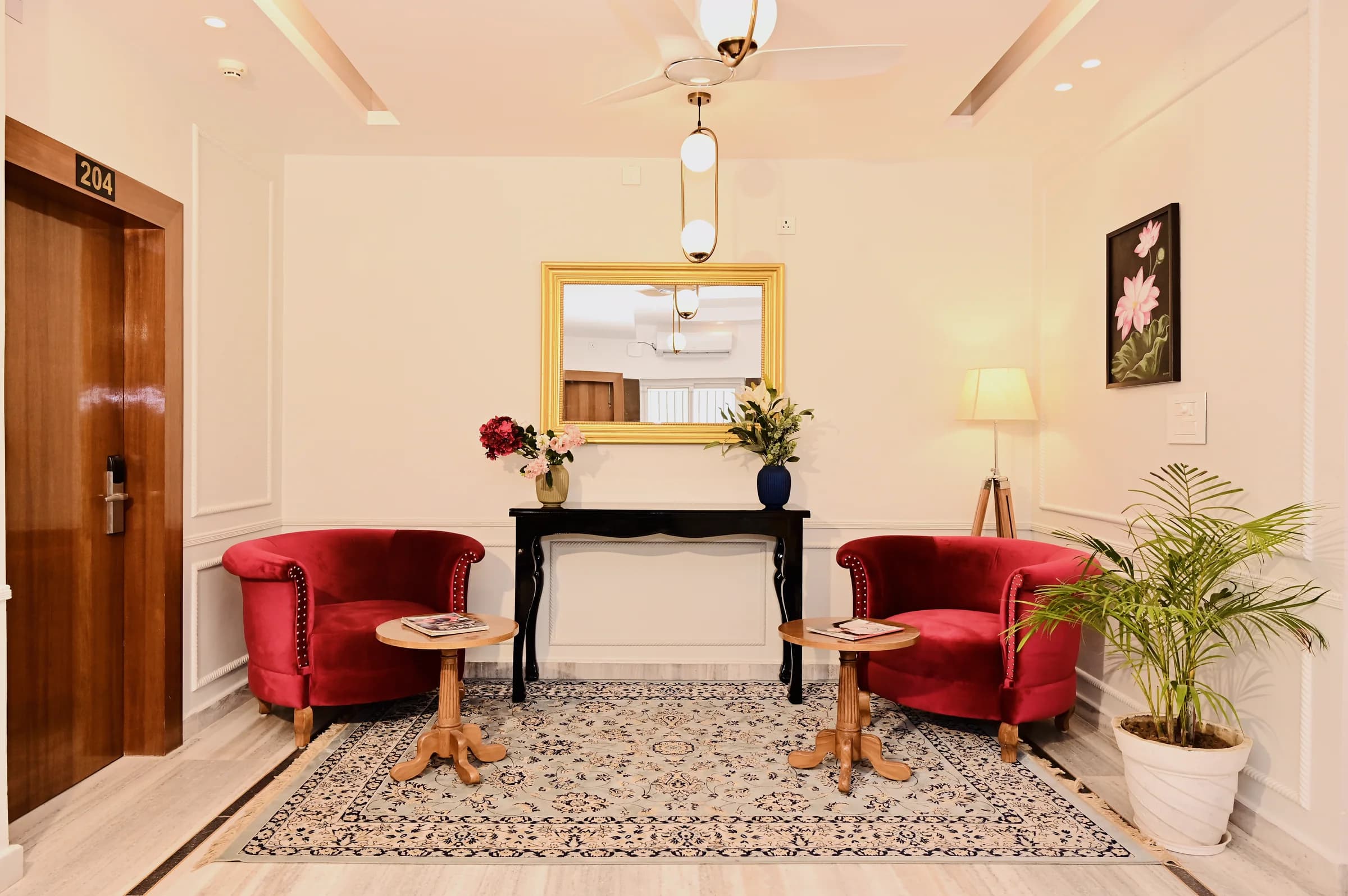 A landing at The Mohua with a gilt mirror, a console table and a pair of red armchairs on a patterned rug